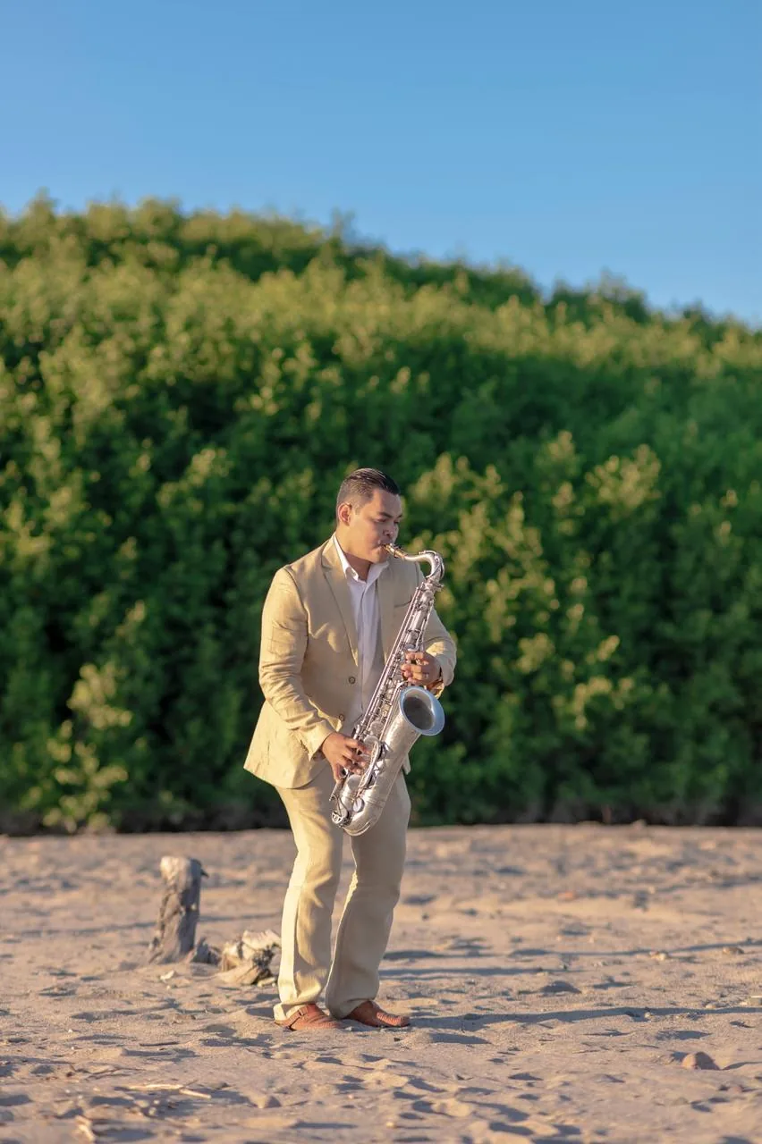 Aleicy Flores tocando sax en playa